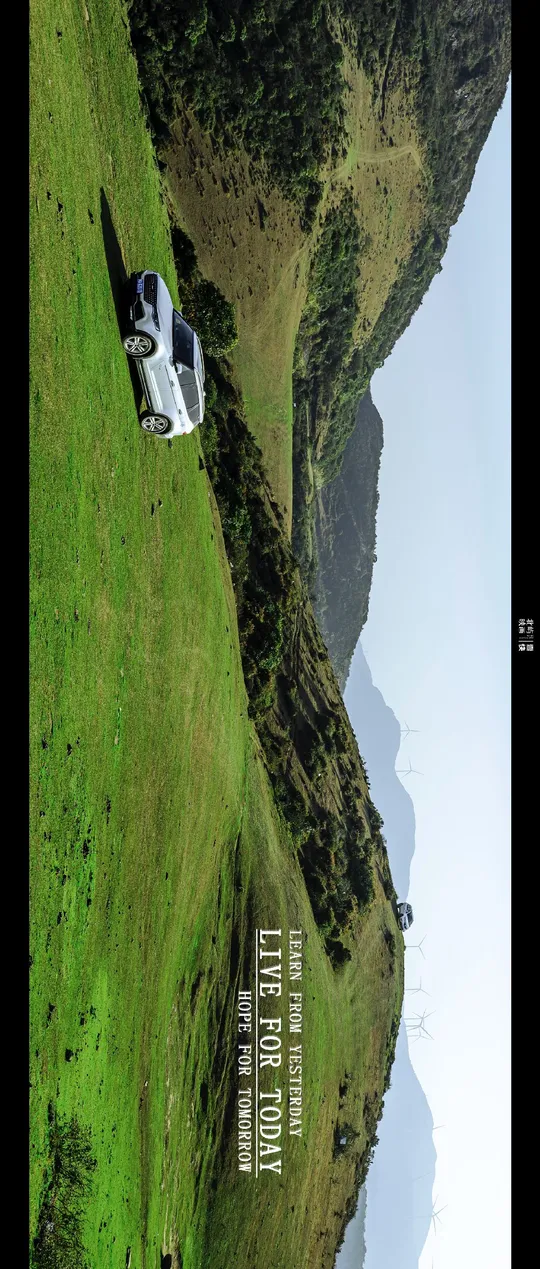 一辆白色汽车或卡车停在一片绿色的山坡上 俯瞰着一片水域和一座山。