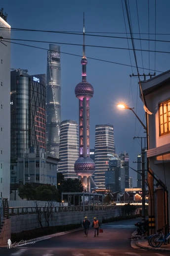 一些人在夜晚的城市天线上走在一条街道前面 旁边有一座高塔。