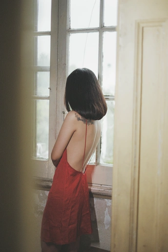 一位穿着红裙子的女人正在房间里的镜子前看着她的倒影