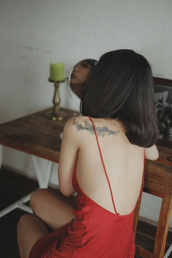 一位穿红裙子的女士 身上有纹身 坐在桌子旁