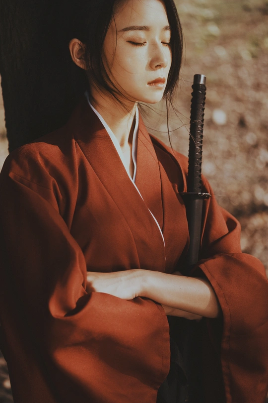 一位穿着红色和服的年轻女子手持雨伞