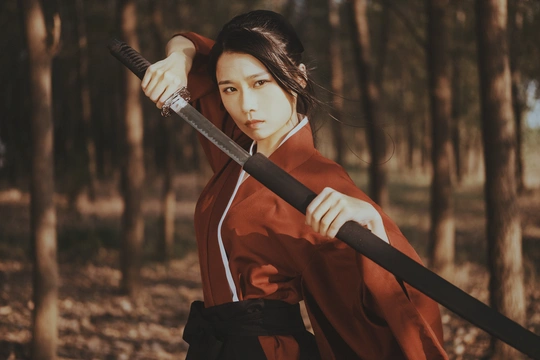 一位身着红和服的年轻女子手持剑在森林中