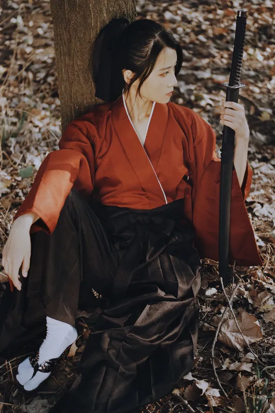 一位穿着和服的女子坐在森林中的一棵树下