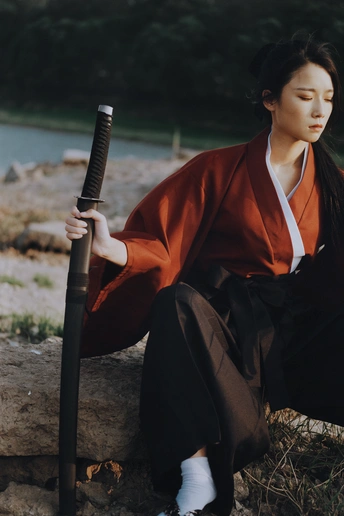 和服着装的女性坐在墙上拿雨伞