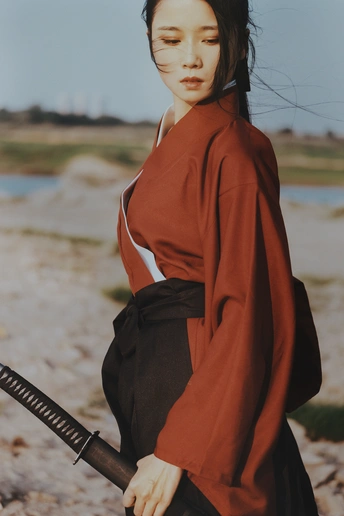 一位穿着红和服的年轻女子在沙滩上持枪