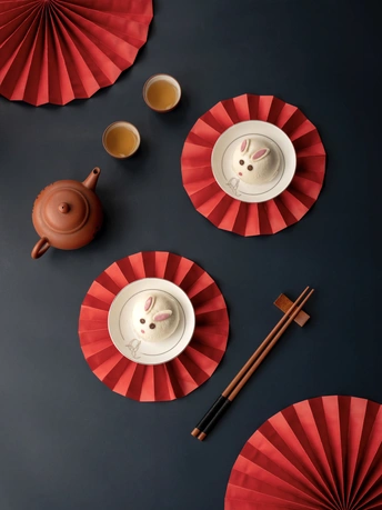 一个带有红色盘子的桌子 茶杯和茶壶。