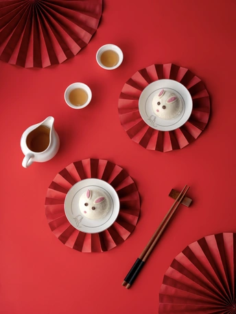 一个红色的桌子 配有白色的杯子和托盘 以及一个风扇。