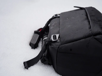 一个黑色的背包 带有一个在雪中的肩带