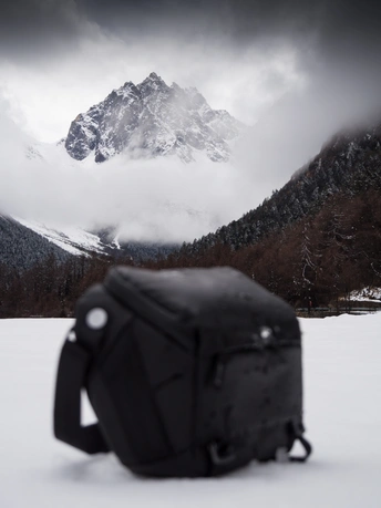 一个背包坐在雪山上