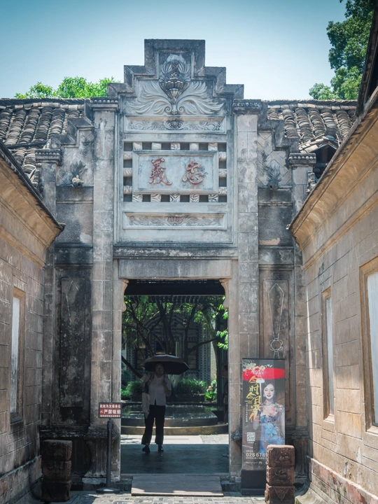 一个拿着雨伞的男人穿过一座古老建筑的庭院。
