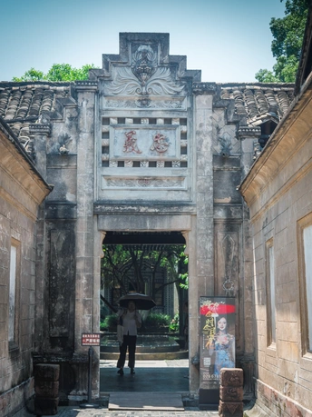 一个拿着雨伞的男人穿过一座古老建筑的庭院。