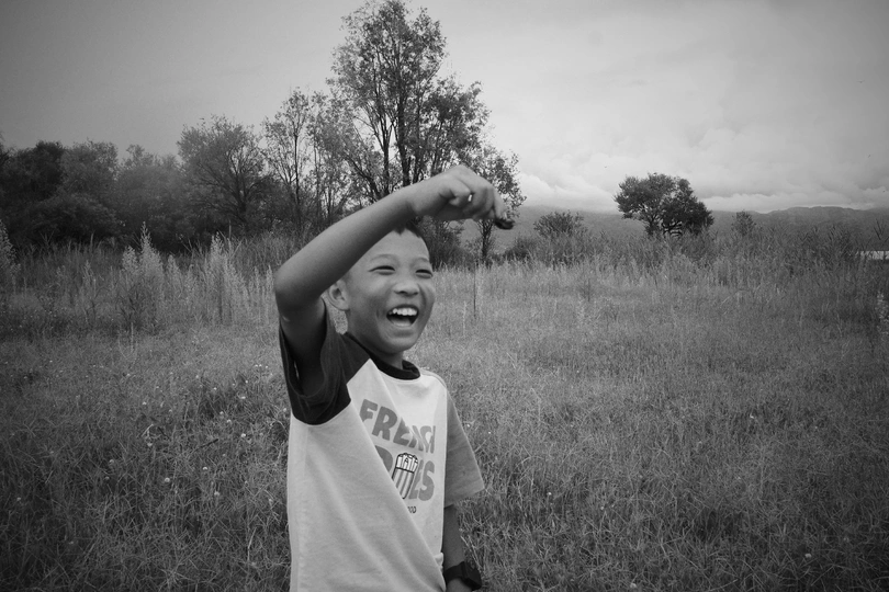 一个小男孩站在草地上 举手过头