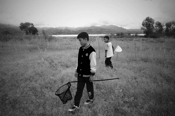 一个小男孩拿着网穿过草地