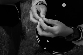 一个人手里拿着一支香烟 一个人手指上戴着婚戒