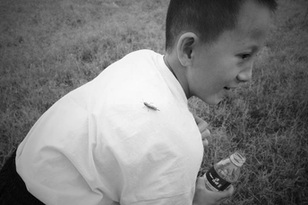 一个小男孩在田野里拿着一个小瓶子