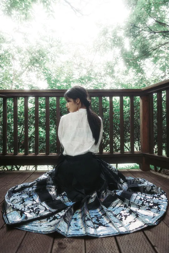 一个穿着白裙子的年轻女子坐在地板上的甲板上