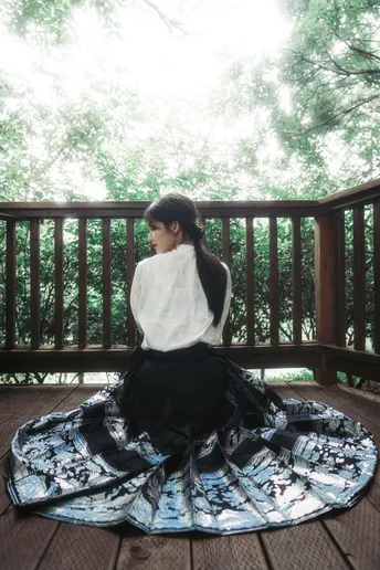 一个穿着白裙子的年轻女子坐在地板上的甲板上