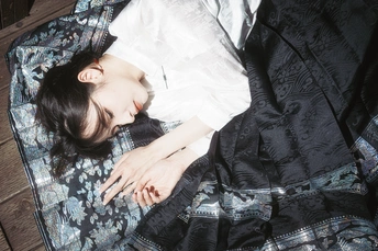 一个年轻女子躺在床上 盖着毛毯 一个箱子放在地板上。