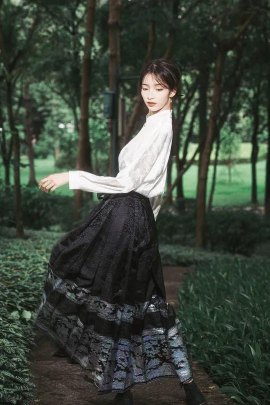 一位穿着白色衬衫和黑色裙子的年轻女子穿过森林