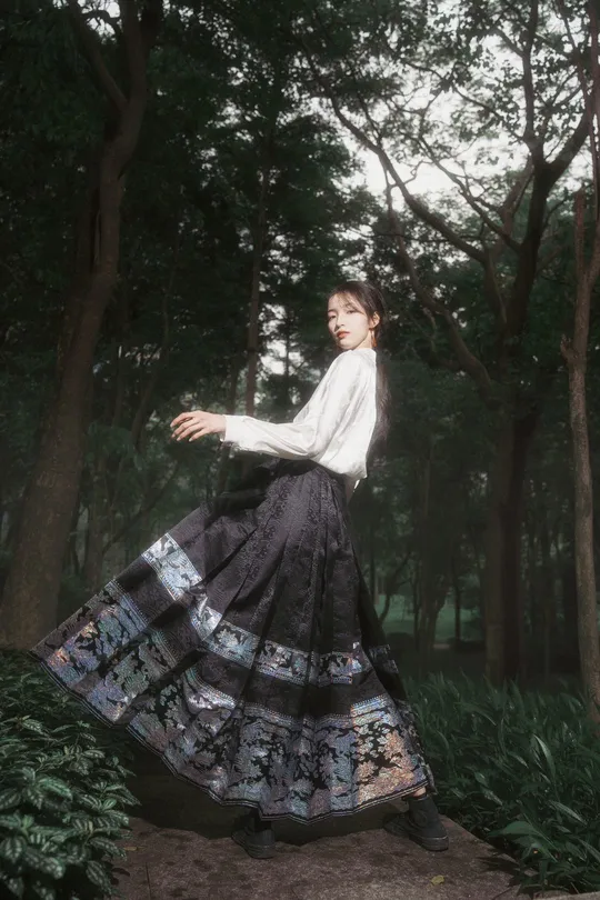 一位穿着黑白连衣裙的年轻女子站在森林中