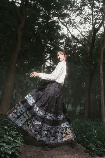 一位穿着黑白连衣裙的年轻女子站在森林中