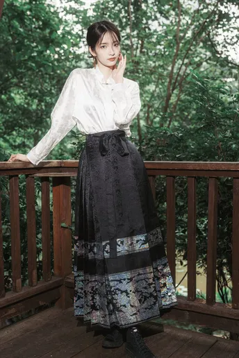 一位穿着黑色裙子和衬衫的年轻女子站在木质甲板上