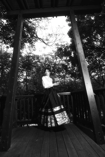 一个穿着黑白裙子的女人站在木质甲板上