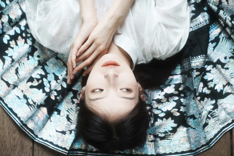 一个穿着白色连衣裙的年轻女子躺在地上 用毛毯遮住眼睛