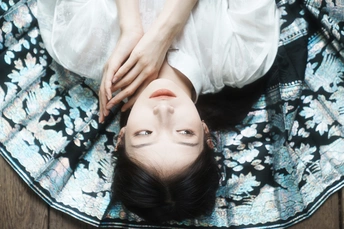 一个穿着白色连衣裙的年轻女子躺在地上 用毛毯遮住眼睛