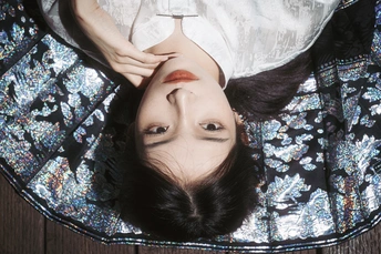 一个穿着白色连衣裙的年轻女子趴在地板上 脸朝下。