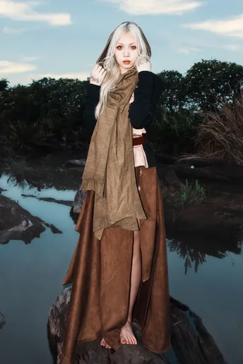 一位穿着棕色衣服的女子在河边的岩石上摆姿势