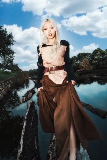 一位穿着裙子和长裙的美丽年轻女子站在河边。