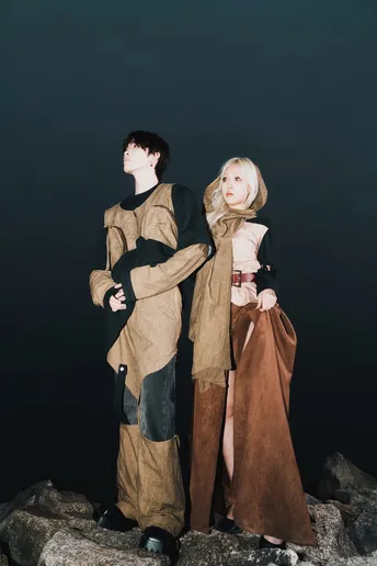 一位男性和一位女性穿着 costumes 站在水边岩石上