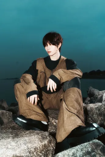 一个年轻人坐在靠近水边的岩石上