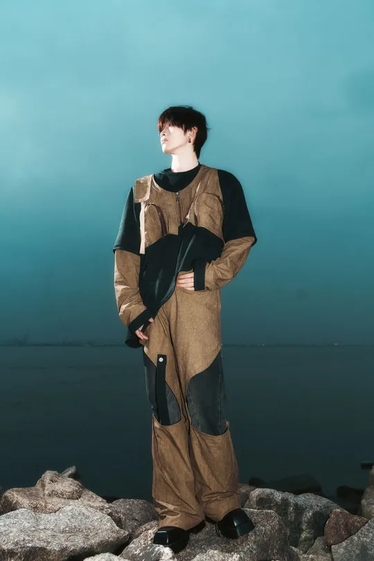 一个人穿着服装站在靠近水域的岩石上