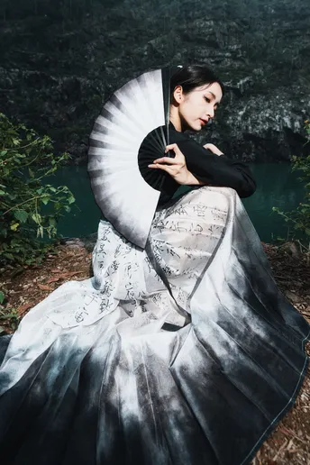 一位穿着白色连衣裙 手持黑色扇子的美丽女士