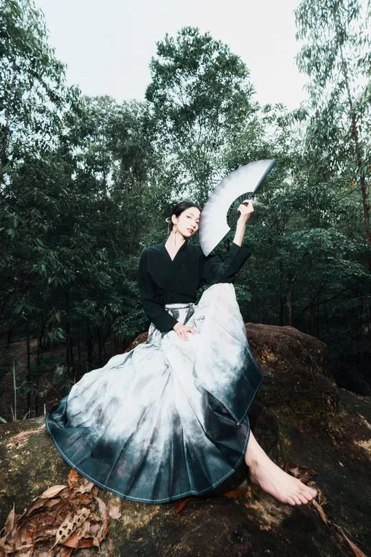 一位女士穿着连衣裙在森林中持着雨伞