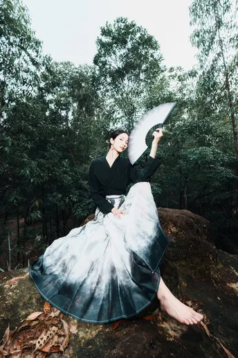 一位女士穿着连衣裙在森林中持着雨伞