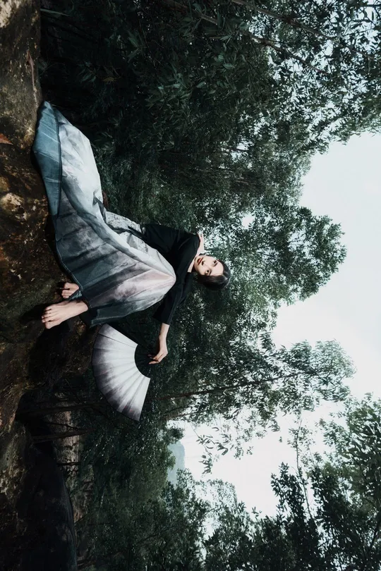 一位站在森林中高耸岩石上的女人