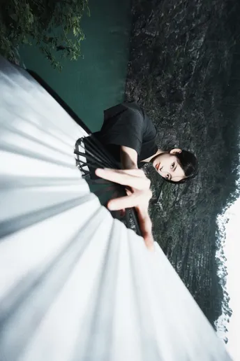 一位穿着白色连衣裙的女人靠近一棵树。