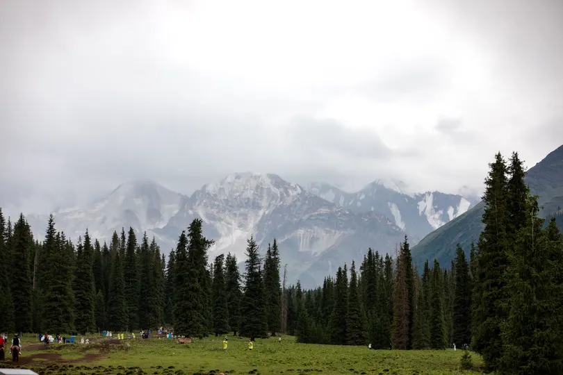背景是青山绿水 有树木、人和山峦。