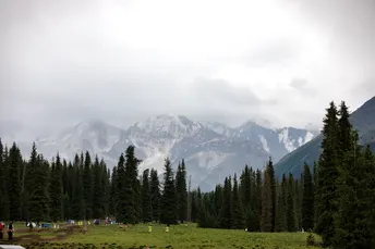 背景是青山绿水 有树木、人和山峦。