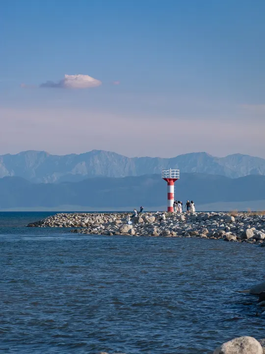位于水域中央一个小岛附近 岩石海岸上的一个红色和白色的灯塔