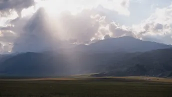 远处的山谷里群山环绕 天空中阳光透过云层洒下光芒。