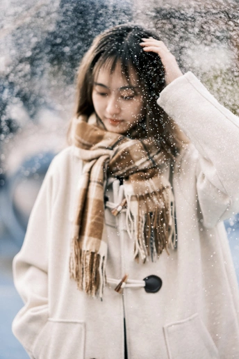 一位穿着白色外套和围巾的年轻女子在雪中
