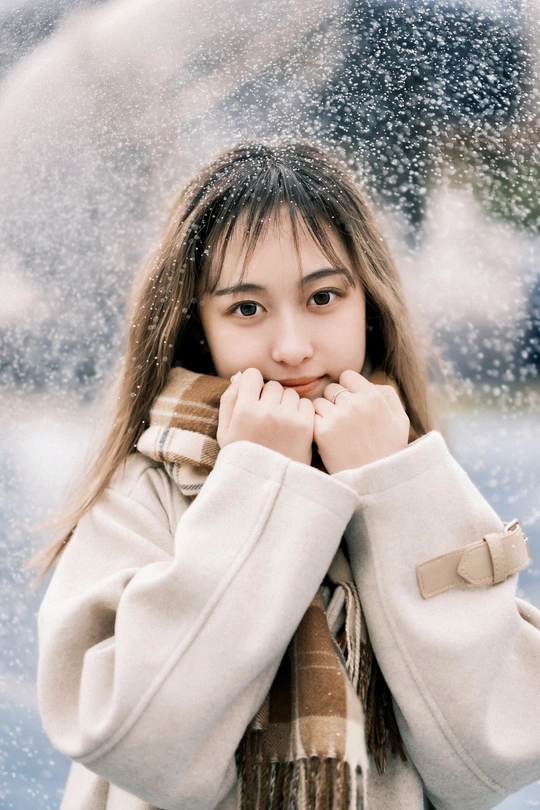 一位穿着外套和围巾的年轻女子站在雪中