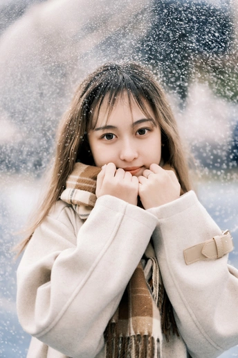 一位穿着外套和围巾的年轻女子站在雪中