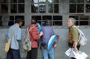 一些人站在一栋老建筑前面排队。