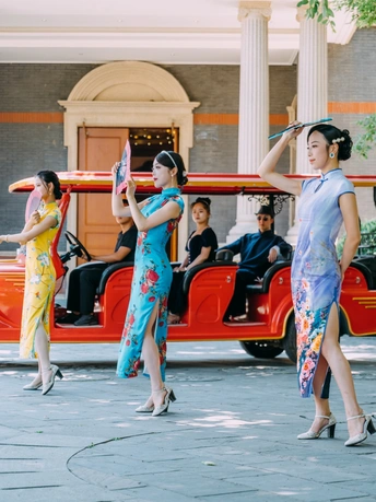 穿传统服装的舞者在红色汽车前举着雨伞