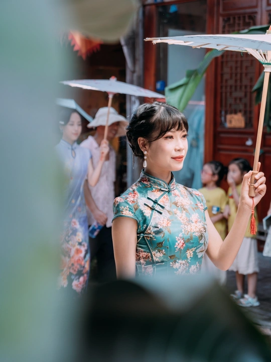 一位穿着连衣裙的年轻女子打着伞走在街上